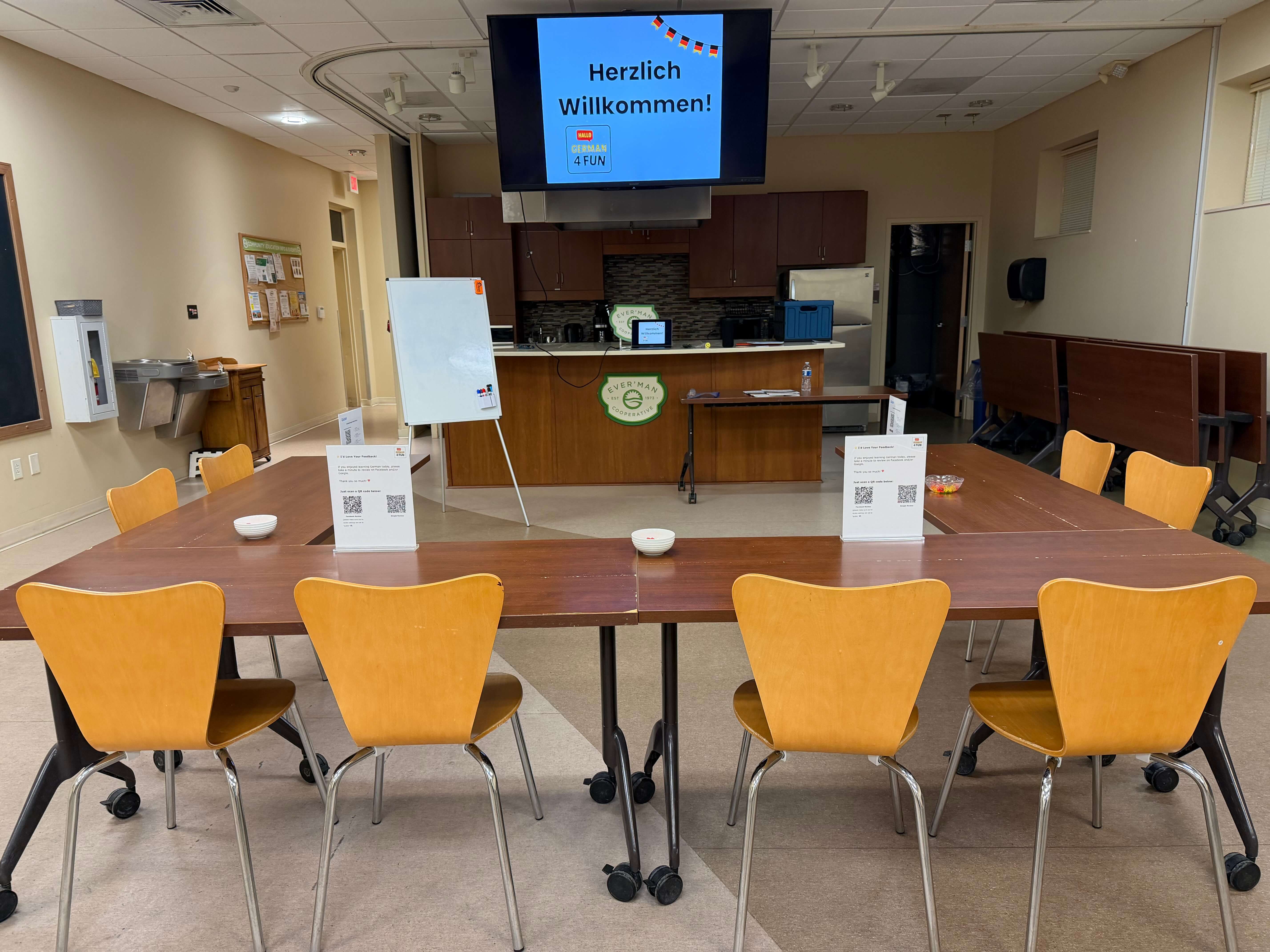 German4FUN classroom in Pensacola set up for a German language class with a ‘Herzlich Willkommen’ welcome screen and tables arranged for students.