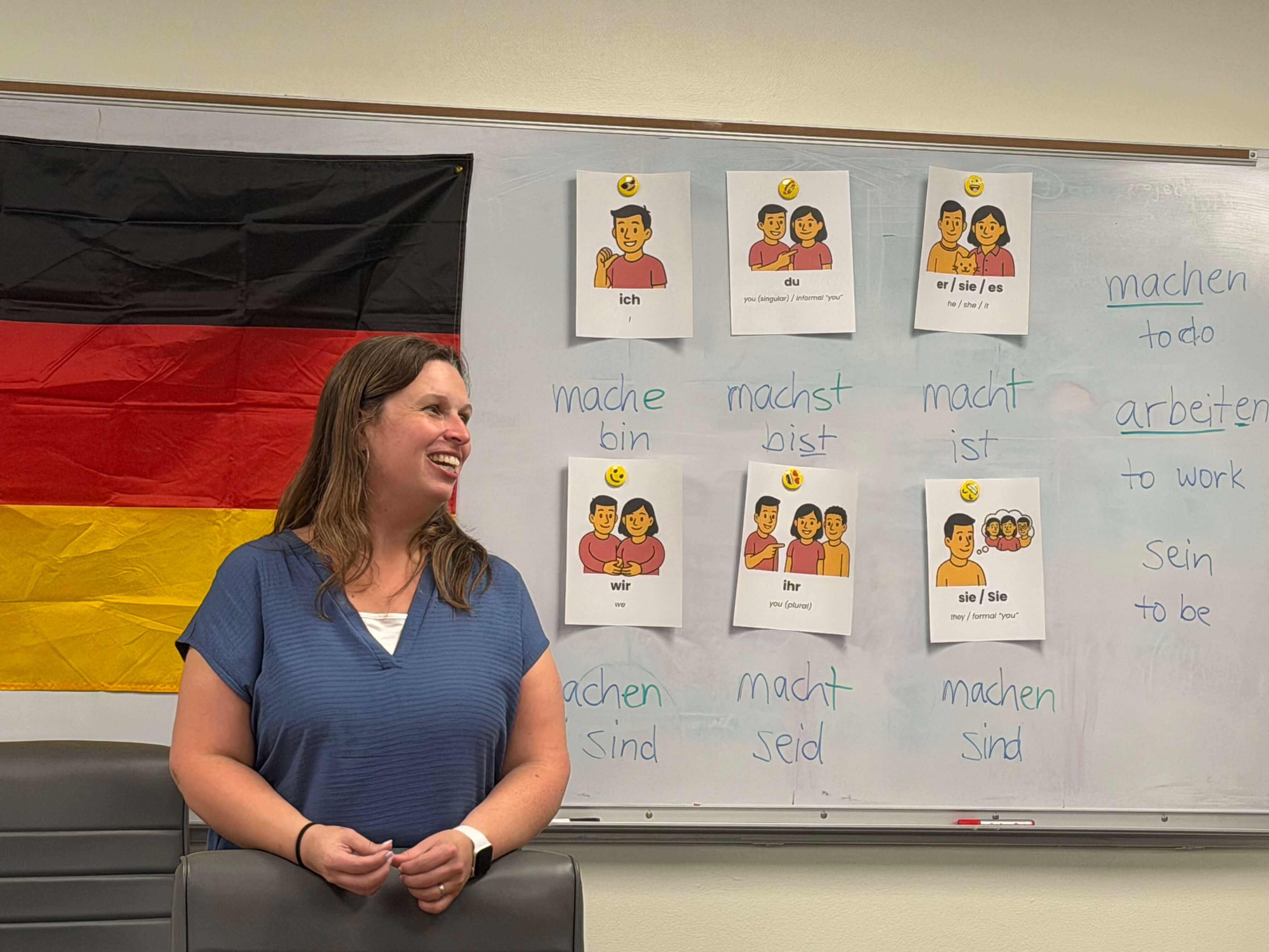 Gesa teaching a German class in Pensacola with verb cards on a whiteboard.